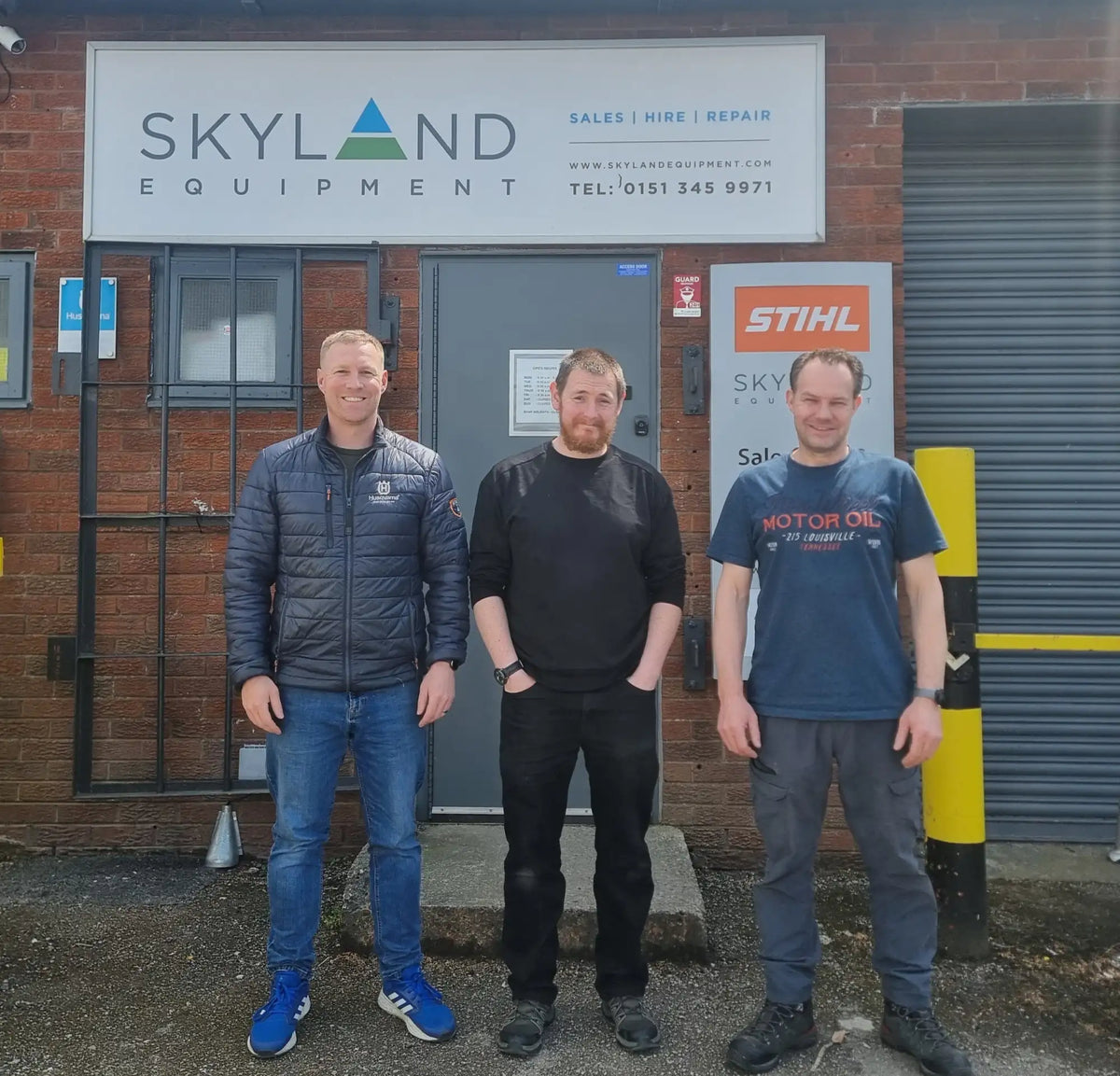 Load video: Three men stand in front of a brick building with signage for ’skyland equipment’ and a stihl logo.